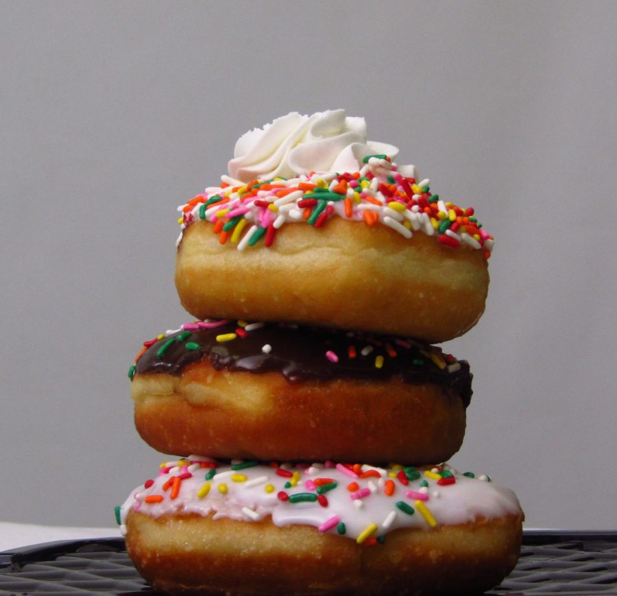 Three sprinkle donuts stacked on top of each other.