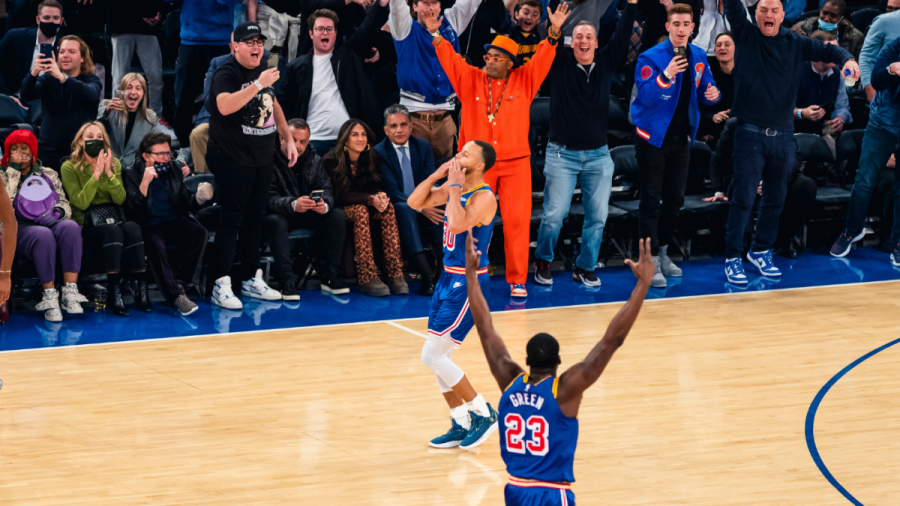Steph Curry blowing a kiss to the fans at Madison Square Garden in New York CIty after breaking the all-time 3-point record, with Draymond Green and Spike Lee celebrating with their hands in the air.