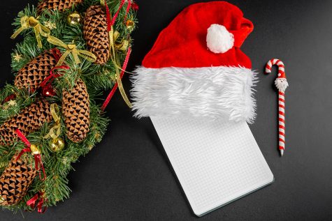 Top view of preparing christmas letter or list on dark background with wreath