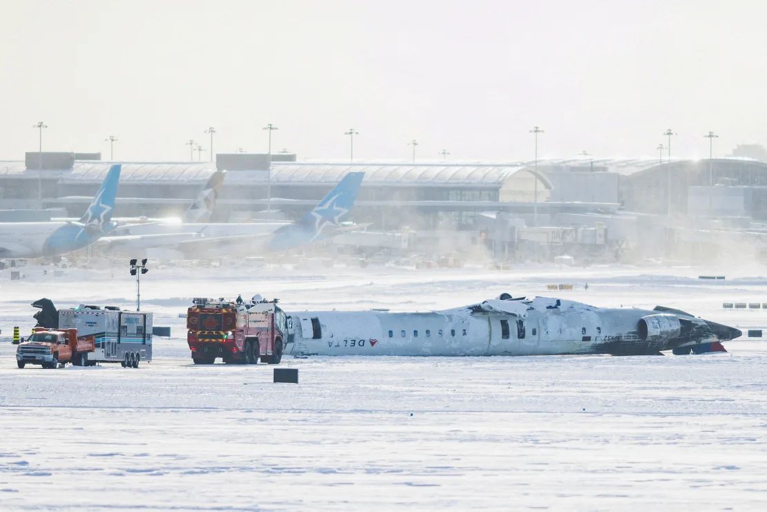 The wreckage of an inverted Delta Airlines plane lies on a runway of the Toronto Pearson International AIrport. 